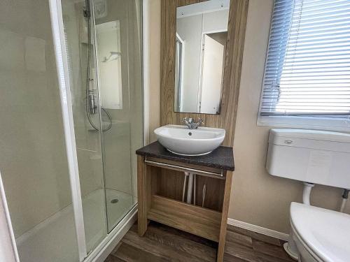 y baño con lavabo y ducha acristalada. en Lovely 6 Berth Caravan With Decking, Close To The Beach In Suffolk Ref 68075bs en Lowestoft