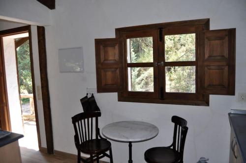 a table and chairs in a room with a window at La cabaña del Burguillo in El Barraco