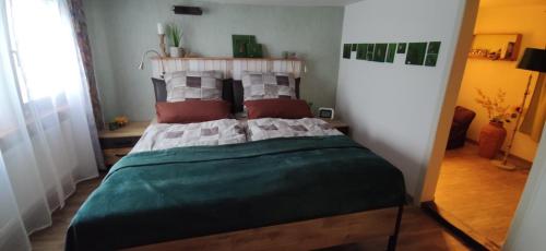 una camera da letto con letto, lenzuola e cuscini verdi di Ferienhaus am Marktplatz a Oberheimbach