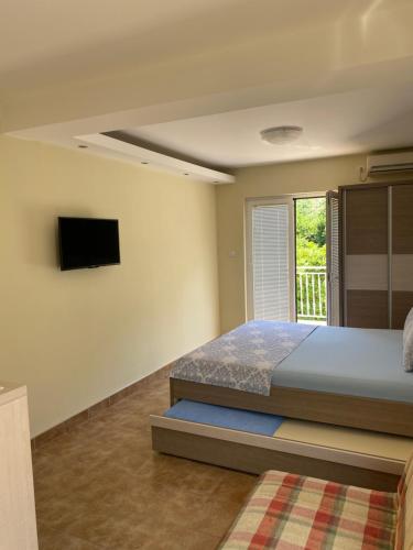 a bedroom with a bed and a tv on the wall at Apartments Lalević in Donji Morinj