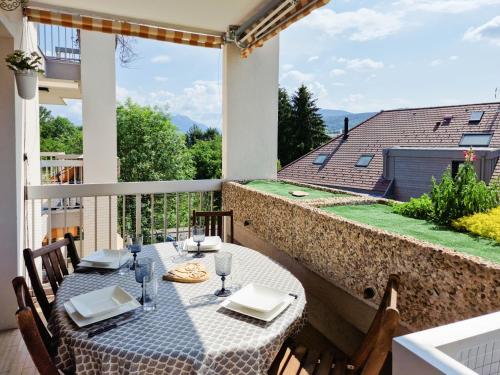 um pátio com uma mesa e cadeiras numa varanda em Annecy-le-Vieux Albigny - Proche Lac - Majord'Home em Annecy