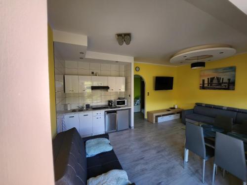 eine Küche und ein Wohnzimmer mit einem Sofa und einem Tisch in der Unterkunft Słoneczny Domek in Podgórzyn