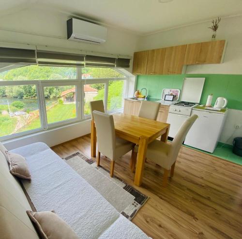 cocina y comedor con mesa de madera y sillas en Unaqua Apartments, en Kulen Vakuf