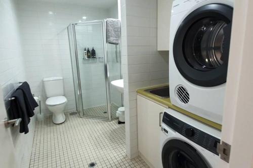 a washing machine in a bathroom with a toilet at Colley 11-11 Sub-Penthouse Luxurious Glenelg in Glenelg