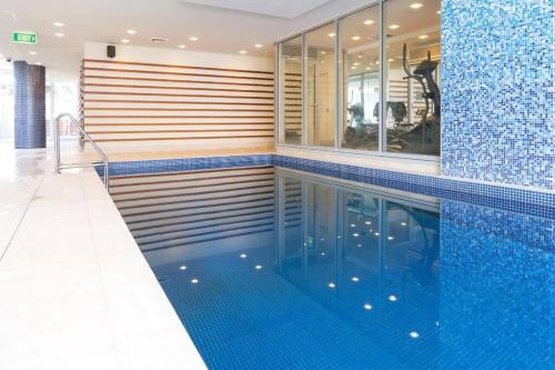 a swimming pool with a blue tiled wall and blue tiles at Colley 11-11 Sub-Penthouse Luxurious Glenelg in Glenelg