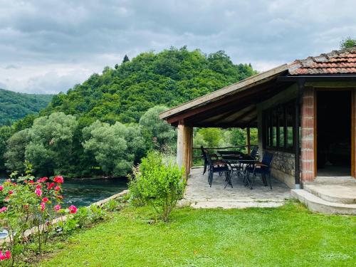 ein Haus mit einem Tisch und Stühlen neben einem Fluss in der Unterkunft Unaqua Apartments in Kulen Vakuf