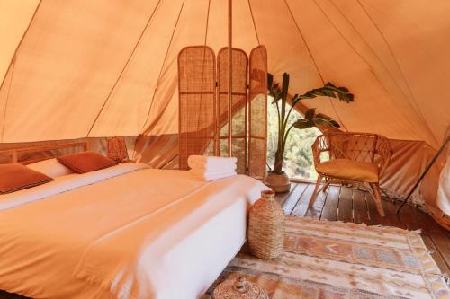1 dormitorio con 1 cama y 1 silla en una tienda de campaña en Dreamsea Mediterranean Camp, en Benitachell