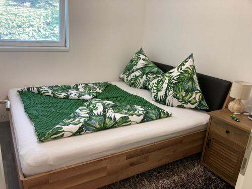 Una cama con almohadas verdes y blancas. en Diófa Vendégház en Fonyód