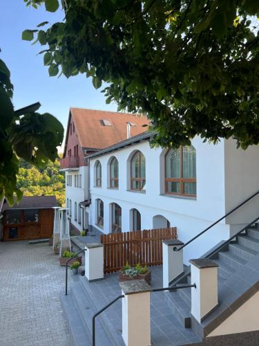 a large white building with a wooden fence at Restaurace a penzion U svaté Barbory in Řehlovice