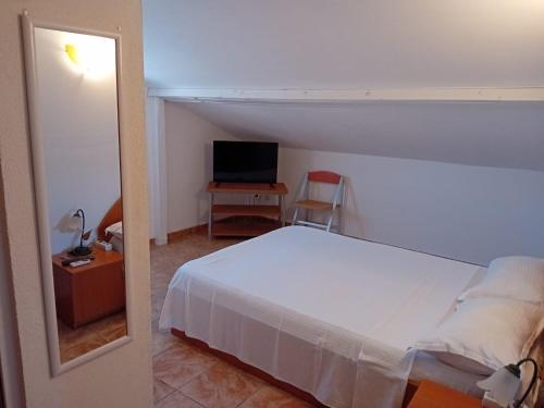 a bedroom with a white bed and a television at casa andrei m in Eforie Sud