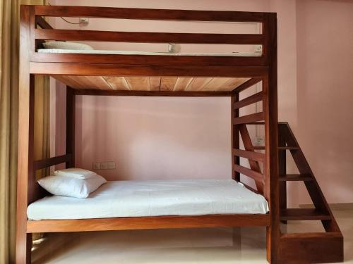 Cette chambre comprend un lit superposé en bois avec un matelas blanc. dans l'établissement Cross Ceylon, à Negombo
