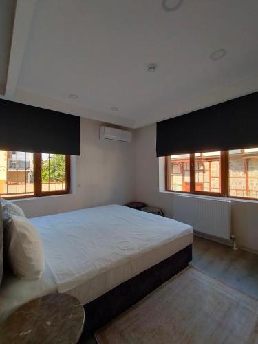 a bedroom with a large bed with two windows at Gala Otel Edirne in Edirne