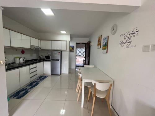 a kitchen with white cabinets and a table and chairs at The Van Gogh Loft at Selesa Hillhomes in Bukit Tinggi