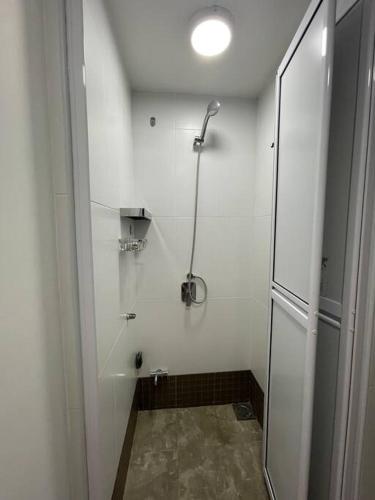 a white bathroom with a shower with a glass door at The Van Gogh Loft at Selesa Hillhomes in Bukit Tinggi