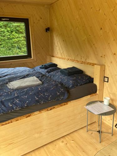 a bed in a wooden room with a window at Obytný kontejner Cabin Stars in Zátor