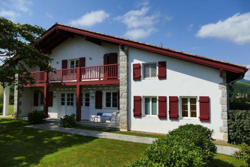 Une grande maison blanche avec volets rouges dans l'établissement BaskoParadis I Eco-Gites I Calme I Vue I Ânes I Jardin I Montagne I Nature, à Louhossoa
