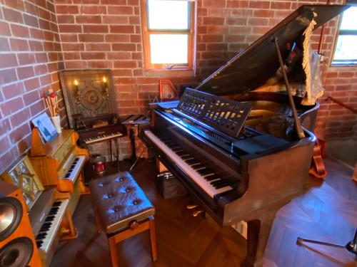 un piano en una habitación con una pared de ladrillo en 猫とピアノと星空のリゾートブティックコテージ - Starry Forest Cottage Okinawa - en Onna