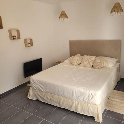 une chambre avec un lit blanc et une télévision à écran plat dans l'établissement Appartement calme et nature, à Saint-Jean-de-Serres