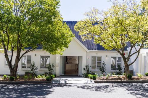 a white house with trees in front of it at Riebeeck Villa - 5 min walk to Franschhoek Central in Franschhoek