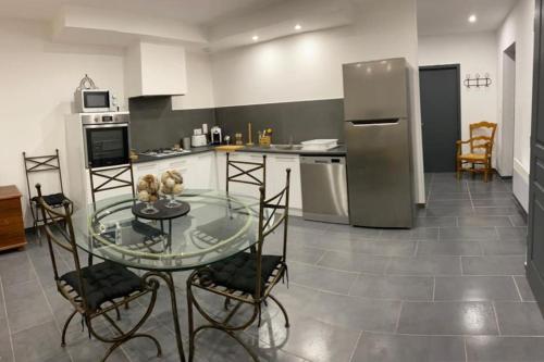 une cuisine avec une table en verre et un réfrigérateur dans l'établissement Appartement calme et nature, à Saint-Jean-de-Serres