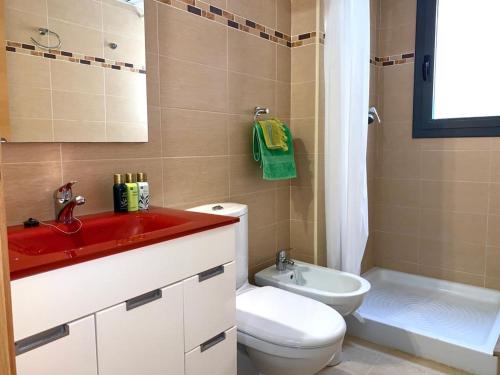 uma casa de banho com um lavatório vermelho, um WC e uma banheira em TROPIKANA em Miami Platja