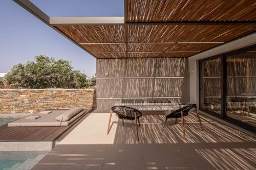 a patio with two chairs and a bed and a pool at Yenesis Seaside Retreat - Adults only over 15 in Tinos Town