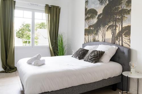 une chambre avec un lit avec des draps blancs et des oreillers dans l'établissement Appart Neuf, parking et plage, à Andernos-les-Bains