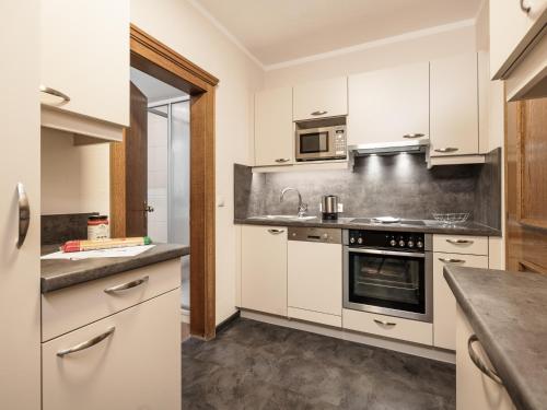 una cocina con armarios blancos y electrodomésticos de acero inoxidable en MYALPS Pure, en Oetz