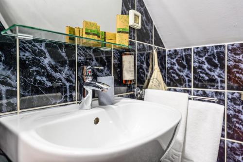 a white sink in a bathroom with black tiles at Cedrus Boutique in Braşov