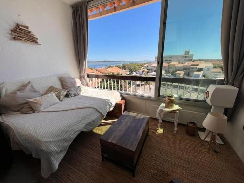 a bedroom with a bed and a large window at Charmant duplex vue mer et étangs ! Clim / Parking in Frontignan