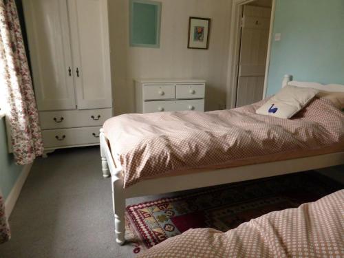 een slaapkamer met 2 bedden, een kast en een tapijt bij The Old Stables of heritage Tregrehan Garden Cottages on South Coast in St Austell