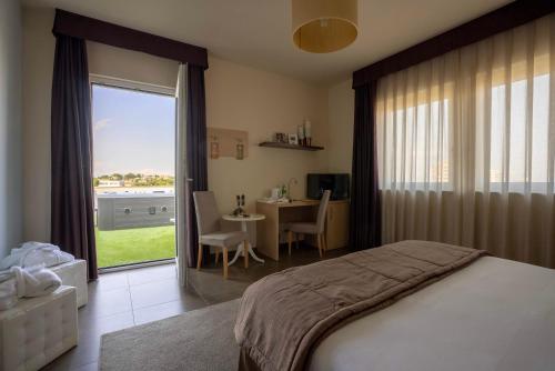 una camera con letto, tavolo e finestra di Hotel Torre Del Sud a Modica