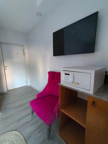 a living room with a pink chair and a flat screen tv at Gala Otel Edirne in Edirne