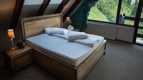 a bed with white sheets and pillows in a room with a window at Pensiunea Poiana Izvoarelor in Vatra Dornei