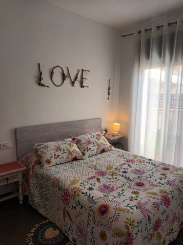 1 dormitorio con 1 cama con una señal de amor en la pared en Gran terraza con piscina, en Sant Jaume d'Enveja