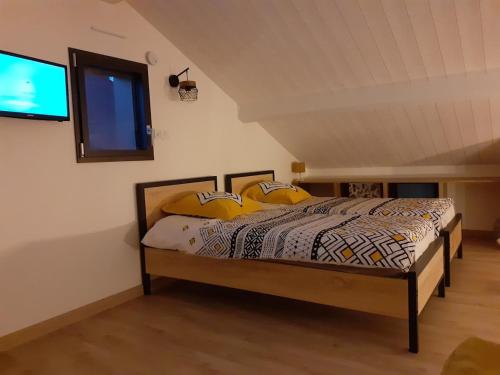 ein Schlafzimmer mit einem Bett mit gelben Kissen und einem TV in der Unterkunft Gîte la Chevêche in Treize-Vents