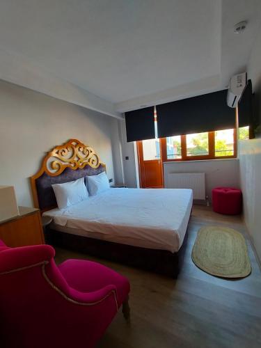 a bedroom with a large bed and a red chair at Gala Otel Edirne in Edirne