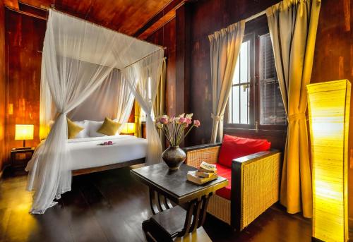 a bedroom with a bed and a vase of flowers on a table at Wat Damnak House in Siem Reap