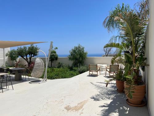 eine Terrasse mit Tischen, Stühlen und Palmen in der Unterkunft Mod Santorini Vegan Boutique Hotel in Fira