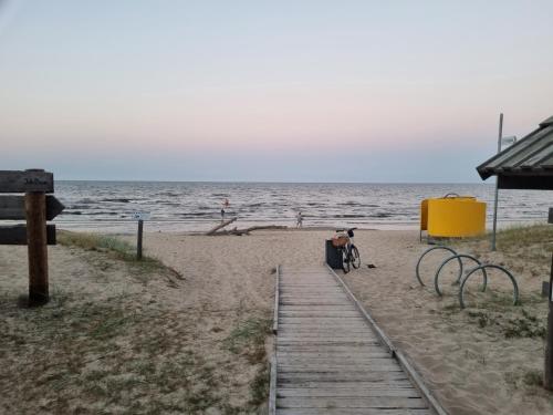 a bike parked on a sandy beach near the ocean at Angren Albatross, SEA & SPA in Ķesterciems
