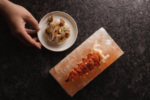 a person holding a plate of food next to a plate of food at Am Pfarrhof - Gourmethotel by Harald Irka in Sankt Andrä-Höch