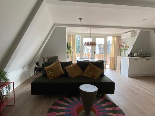 a living room with a black couch and a kitchen at Suite Spot Houten in Houten