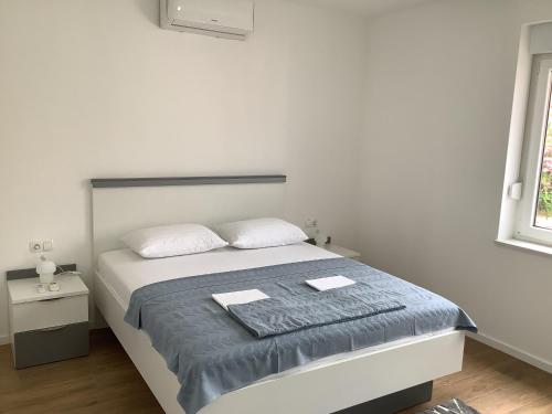 a white bedroom with a bed and a window at Apartments Jozef in Vodice