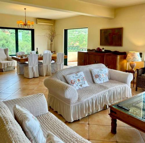 een woonkamer met witte banken en een eetkamer bij Olive Villa in Xirokámbion