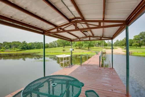a covered deck with a table and chairs next to a body of water at Lake Fork Studio Cabin with Dock and Boat Ramp! in Emory