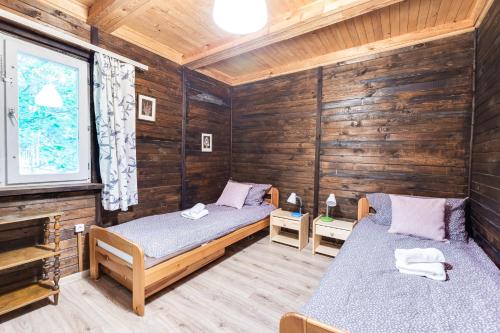 a room with two beds in a wooden cabin at Chata 'Leśne Kurki' in Kurki