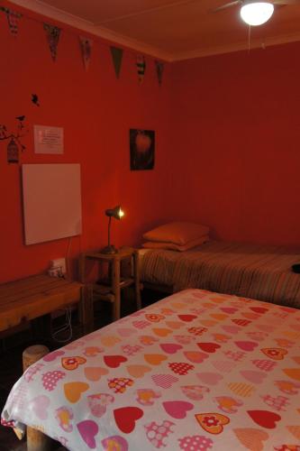 a room with two beds and a table and a white board at Cape Agulhas BACKPACKERS in Struisbaai
