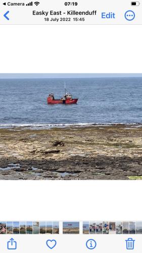 a red boat on the water in the ocean at Wild Atlantic View in Sligo