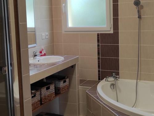 une salle de bain avec un lavabo et une baignoire dans l'établissement AMATHÉE jolie maison au calme avec piscine chauffée, à Soulac-sur-Mer