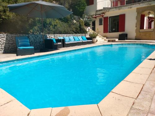 una piscina con sedie blu e ombrellone di T2 de la Bastide Rouge vue exceptionnelle (180°) sur Aix domaine privé T2 indépendant de 37 m2 avec terrasse exposée plein sud Piscine 10 X 5 ad Aix en Provence